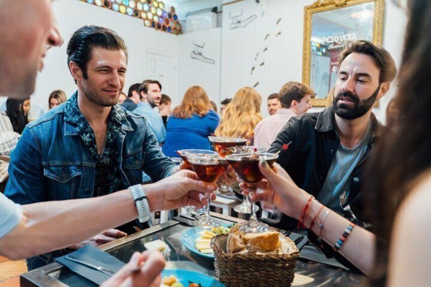 People toasting with drinks at a table with food and a basket. 3