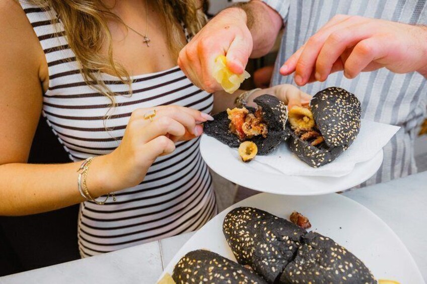 A person holding a food item with sesame seeds. 4