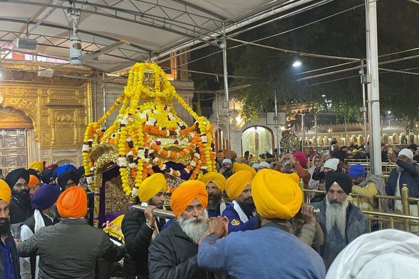 A crowd gathered around a decorated structure, possibly a religious or cultural monument, with people wearing turbans. 3