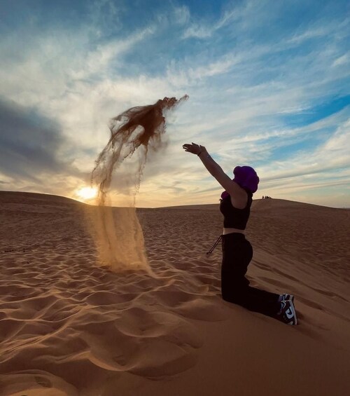 A person in a desert with sand dunes and a sunset in the background. 5