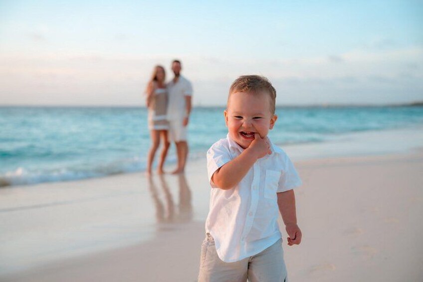A beach with a child in the foreground and a couple in the background. 3