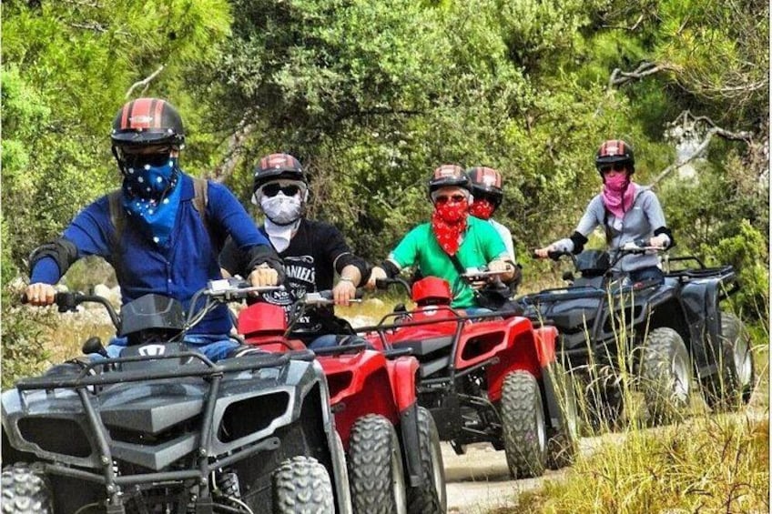 Cuatro personas conduciendo cuatrimotos por un sendero rodeado de follaje. 2