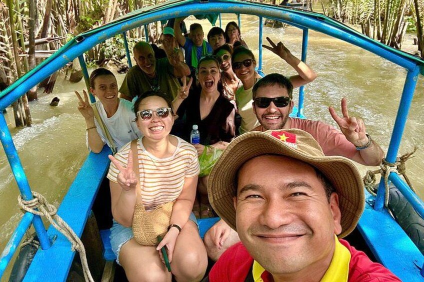A group of people on a boat with a blue railing, surrounded by water and vegetation. 3