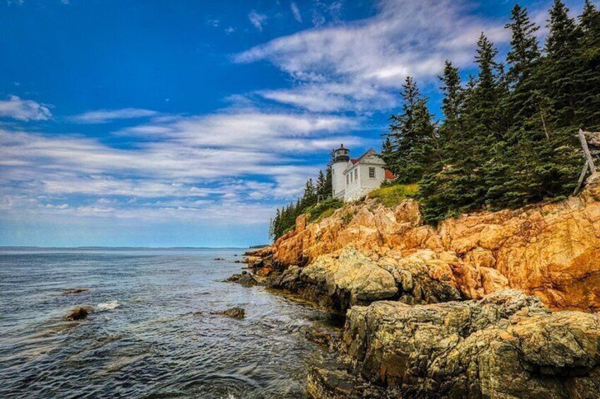 A coastal landscape with a lighthouse, rocky cliffs, and dense forest. 2