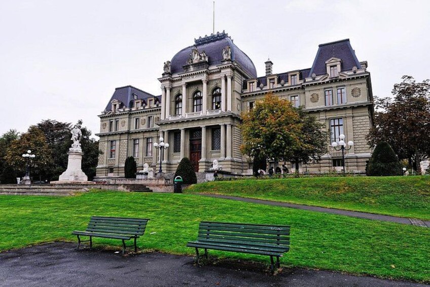 A large, historic building with a dome and columns, surrounded by a well-maintained lawn and two benches. 3