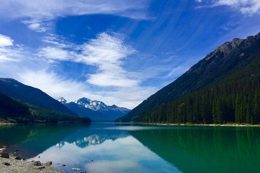 A calm lake surrounded by mountains and dense forests. 4