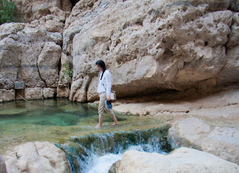 A person walking near a rocky water feature. 3