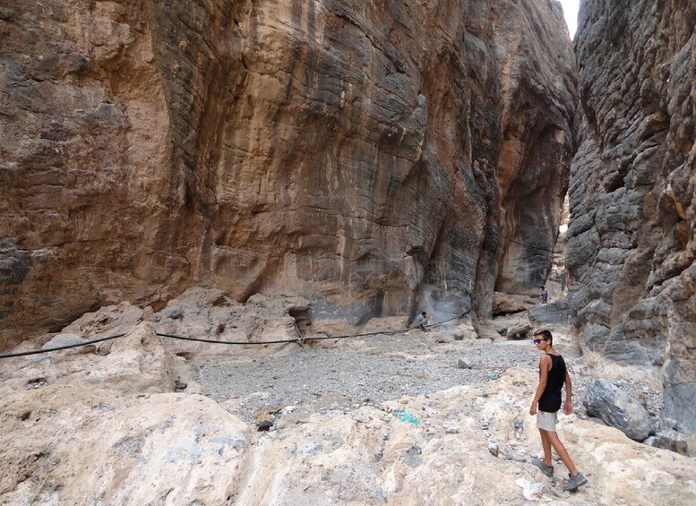 A person standing in a rocky canyon with steep walls and a narrow passageway. 5