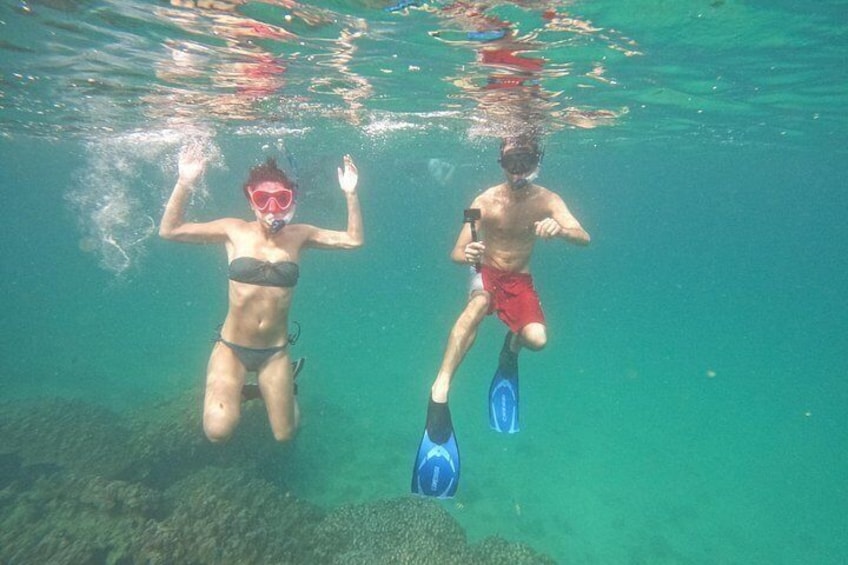Two people snorkeling underwater, one with a snorkel and fins, the other with a snorkel and flippers. 3
