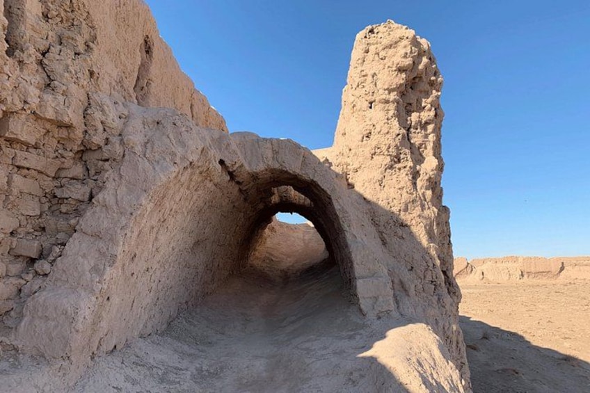 Paesaggio desertico con un'ampia arcata in pietra e un'alta torre stretta. 4