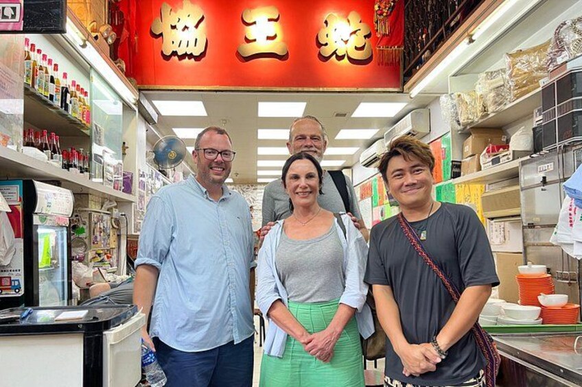 A group of people standing in a store with shelves stocked with various items. 2