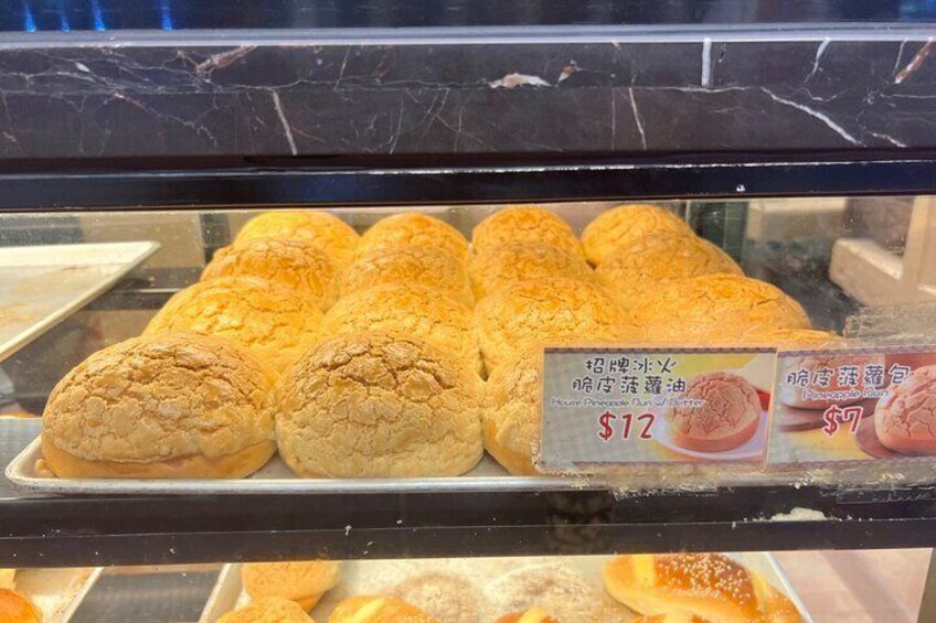 A display case with pastries, including a sign indicating a price of $12 for one item. 5