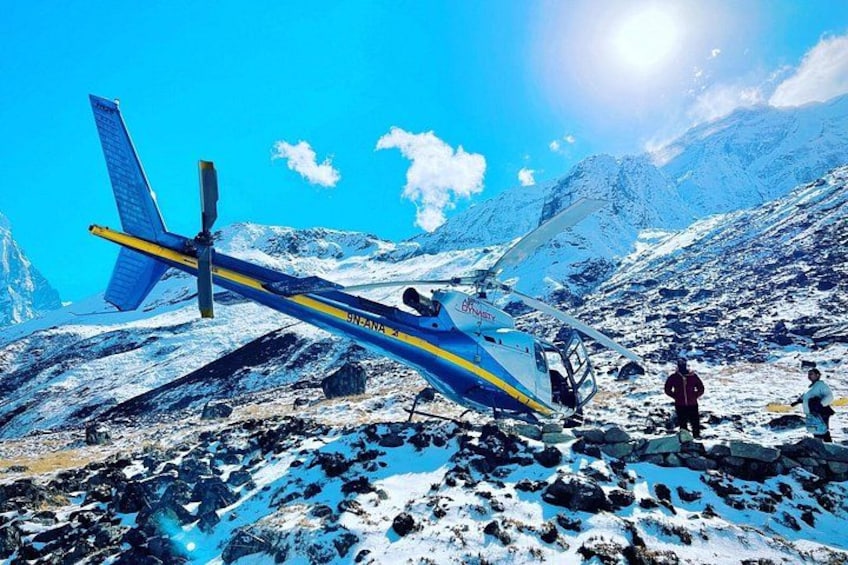 A blue and yellow helicopter on a snowy mountain with a clear sky. 3