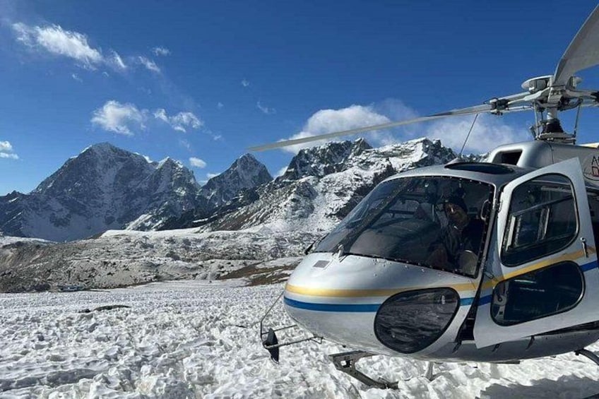 A helicopter parked on snow-covered ground with mountains in the background. 4