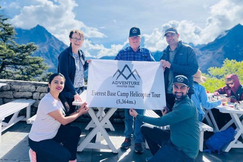 En gruppe mennesker holder et banner forikoptertur til Mount Everest’s foden. 1