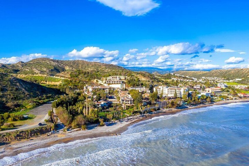 A coastal town with buildings along the beach, a clear blue sky, and hills in the background. 5
