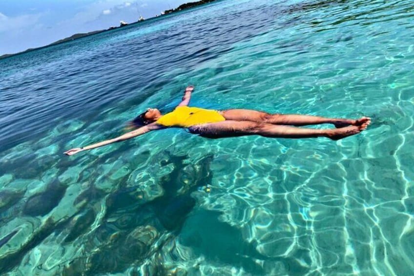 A person floating on a clear blue sea. 5