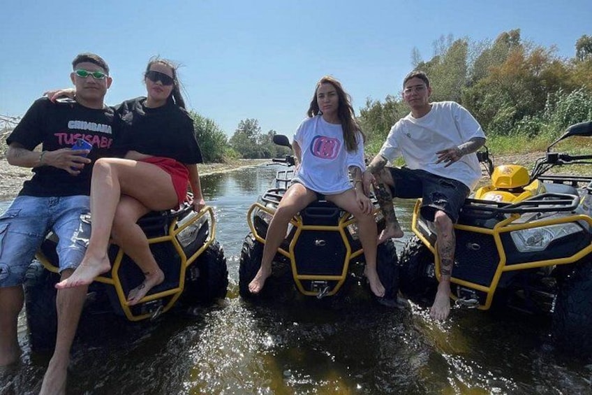 Quatre personnes sur des véhicules tout-terrain (quads) dans une rivière. 4