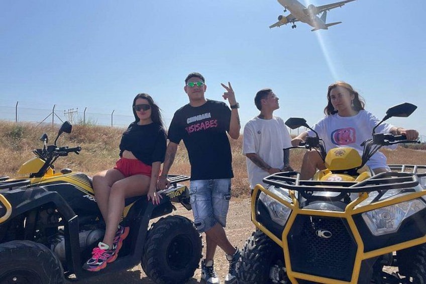 Quatre personnes à bord de quads, avec un avion en arrière-plan. 5
