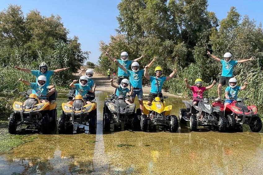 Un groupe de personnes conduisant des quads dans un environnement naturel, avec des arbres et de l’eau. 2