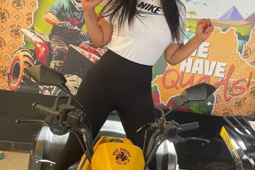 Une personne se tient sur une moto, avec un bidon jaune d’essence, une carte et une affiche motivante en arrière-plan. 3