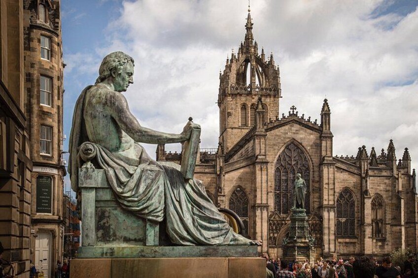 A statue of a seated figure in front of a Gothic-style church. 3