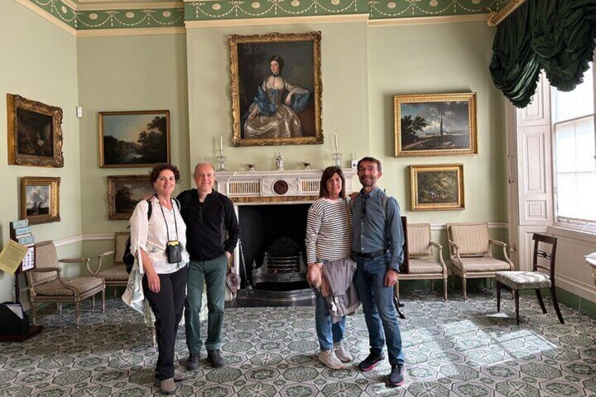 A room with a fireplace, framed paintings, and a patterned floor. 2