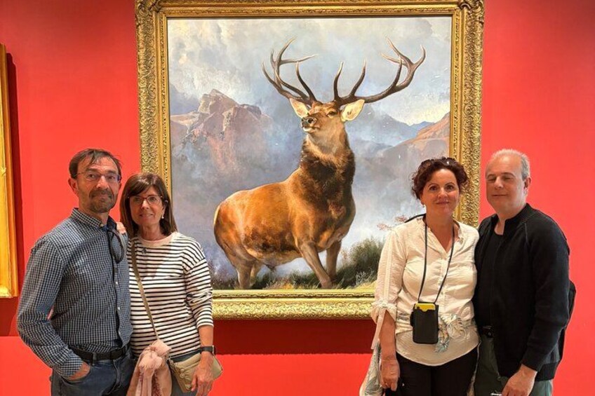 A group of people standing in front of a framed painting of a deer. 2
