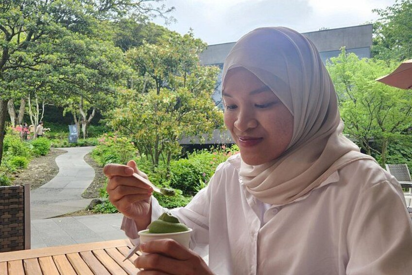 A person in a white hijab sitting at an outdoor table with a cup of green tea. 3