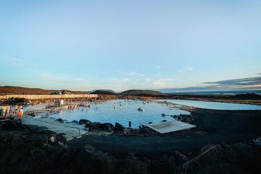 A geothermal spa with people swimming and walking around. 4