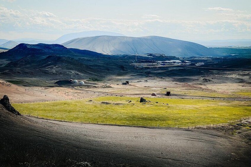 A mountainous landscape with a clear sky, a winding road, and scattered buildings. 3