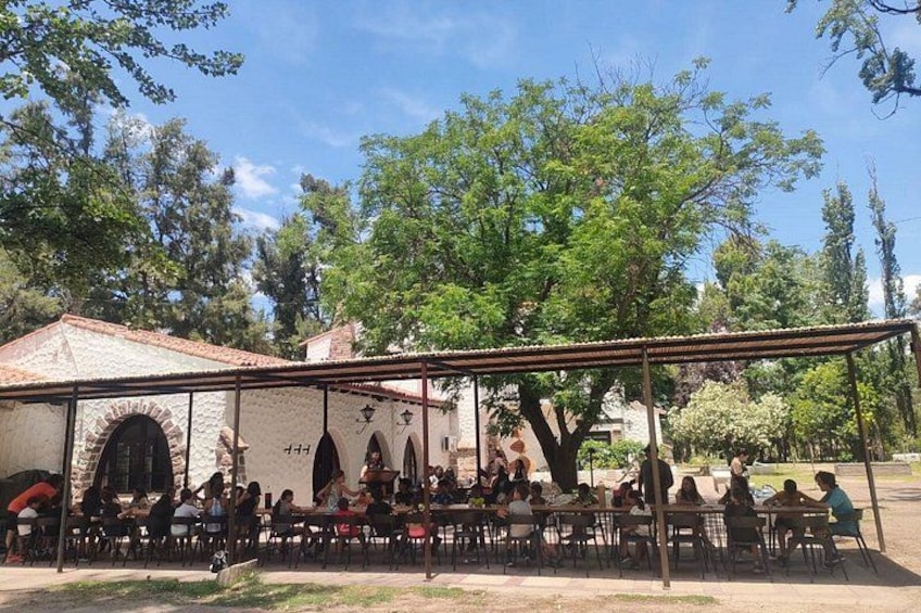 An outdoor dining area with people seated at tables under a covered structure. 2