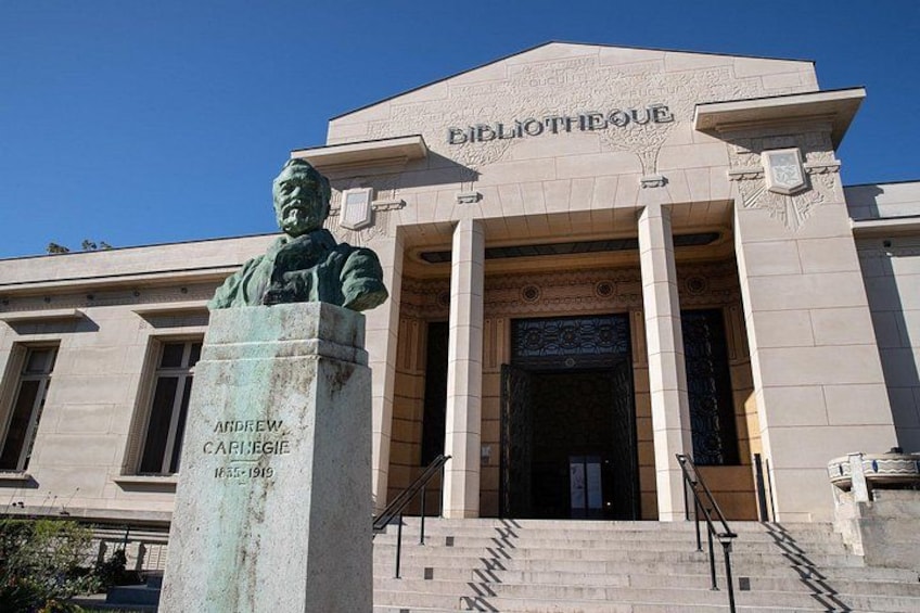 Un edificio con una statua di Andrew Carnegie davanti, con la scritta 'Bibliotheque'. 1