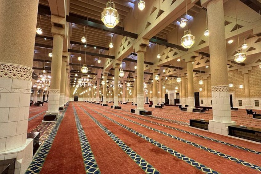 Un grand hall spacieux, avec des rangées de chaises, une moquette à motifs et des luminaires suspendus. 2