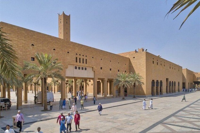 Un grand bâtiment historique, doté d’une haute tour, de palmiers et d’une cour intérieure où se promènent des gens. 5