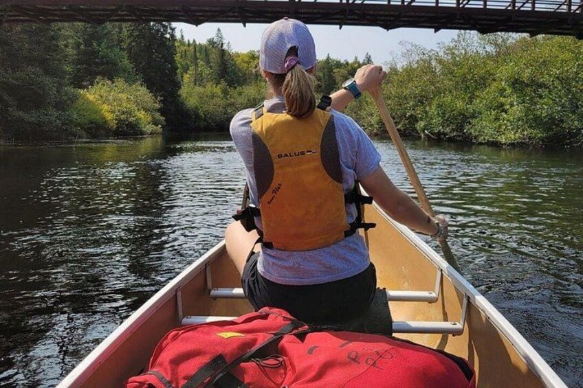 Une personne dans un canoë sur une rivière, portant un gilet de sauvetage et une casquette. 2