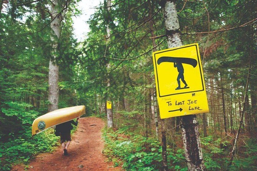 Un sentier forestier avec un panneau jaune indiquant la direction à suivre pour rejoindre le lac Lost Joe. 3