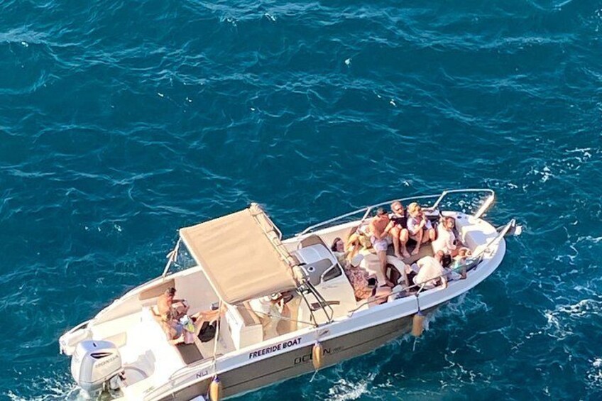 A boat with people on board, sailing on blue water. 1
