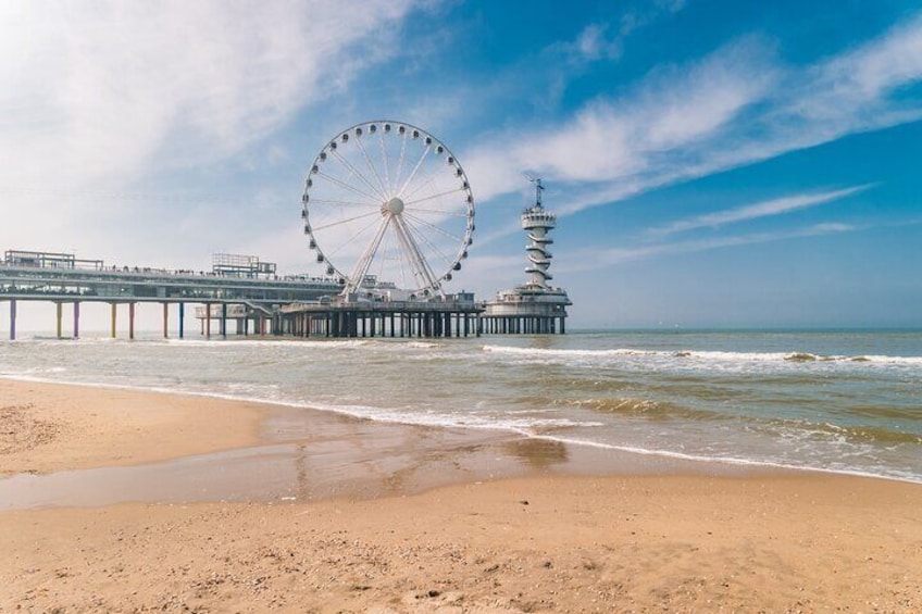 A beach with a pier, a large Ferris wheel, and a tower. 5