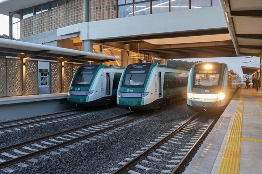 En modern tågstation med tre tåg på spåren, en överbyggd perrong och en byggnad med en fasad som har ett gittermönster. 5