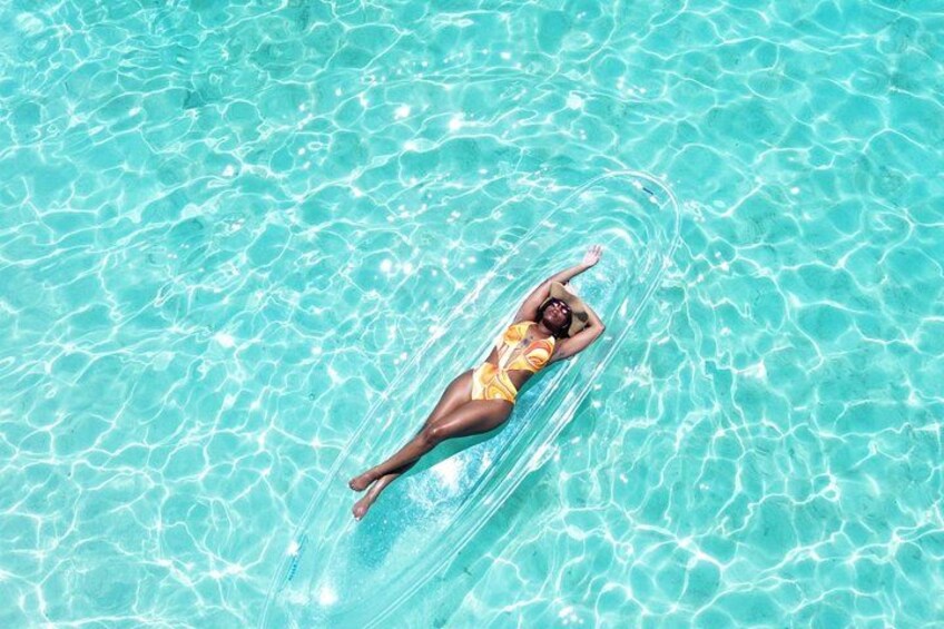 A person floating on a clear blue water surface. 1
