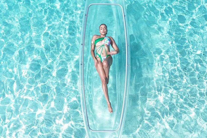 A person floating on a clear inflatable pool in a body of water. 2
