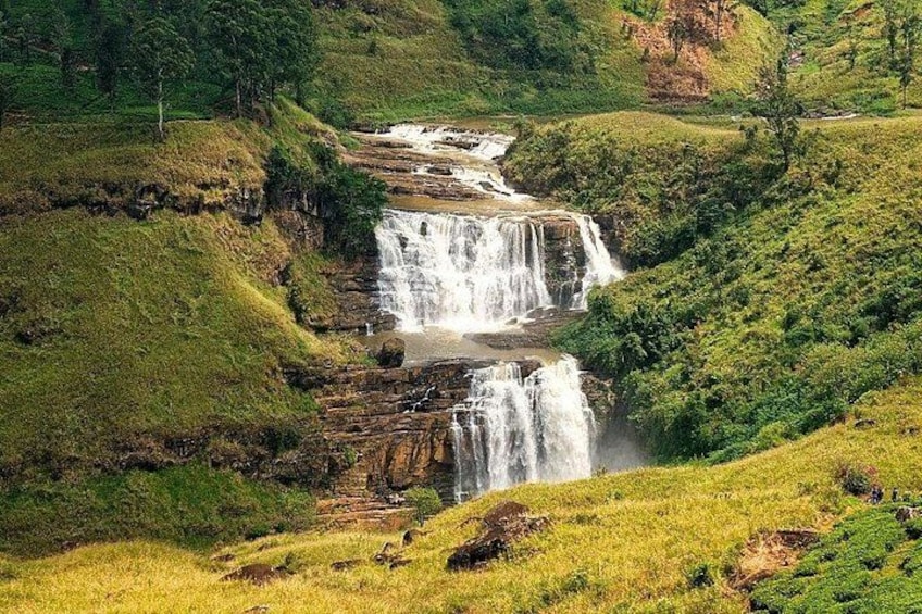 A multi-tiered waterfall cascading through a lush, green valley. 2