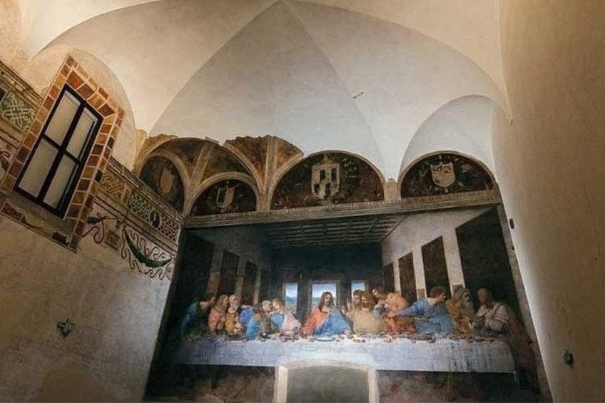 A fresco of the Last Supper in a church with arched ceilings and a window. 1