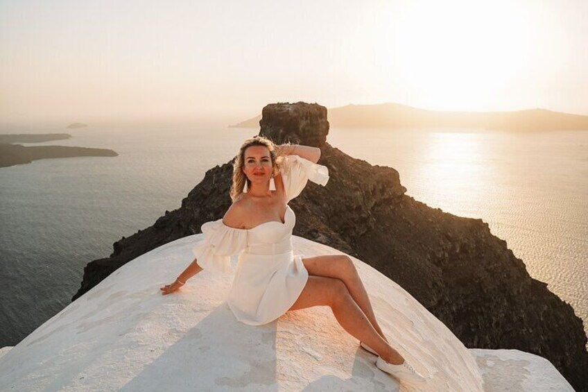 A person in a white dress sitting on a rock by the sea at sunset. 2