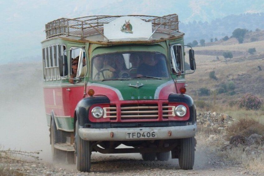 A vintage truck with a license plate TFD406 driving on a dusty road. 5
