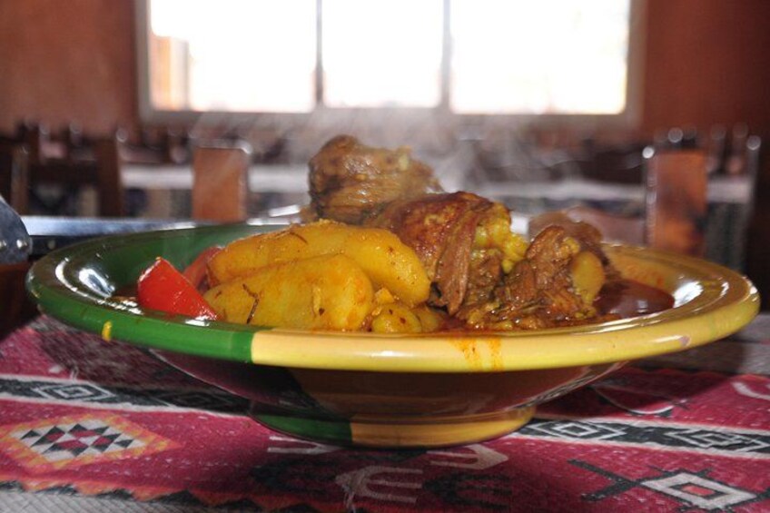 A plate of food with potatoes and meat, possibly a stew, on a table with a patterned tablecloth. 3