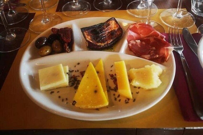 A plate of food with cheese, olives, meat, and a grilled item. 5
