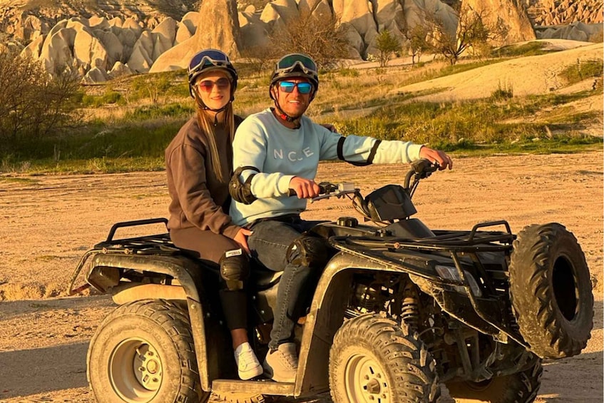 Two people on an ATV in a rocky outdoor setting. 1