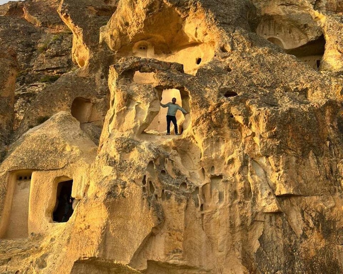 A person standing in a cave-like structure with multiple openings. 2